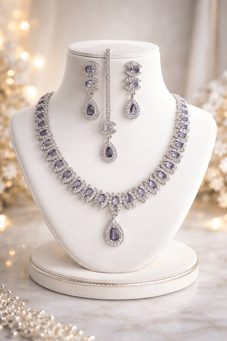 Purple gemstone necklace and earrings on a white mannequin bust with a soft blurred background.