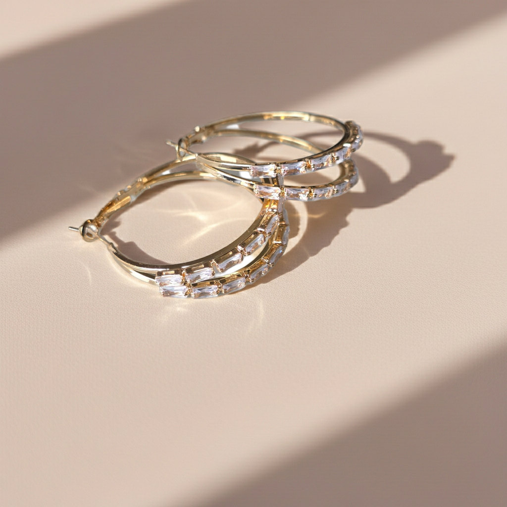 Gold hoop earrings with clear stones on a beige surface