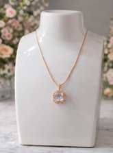 Rose gold necklace with a pendant on a white mannequin bust against a floral background