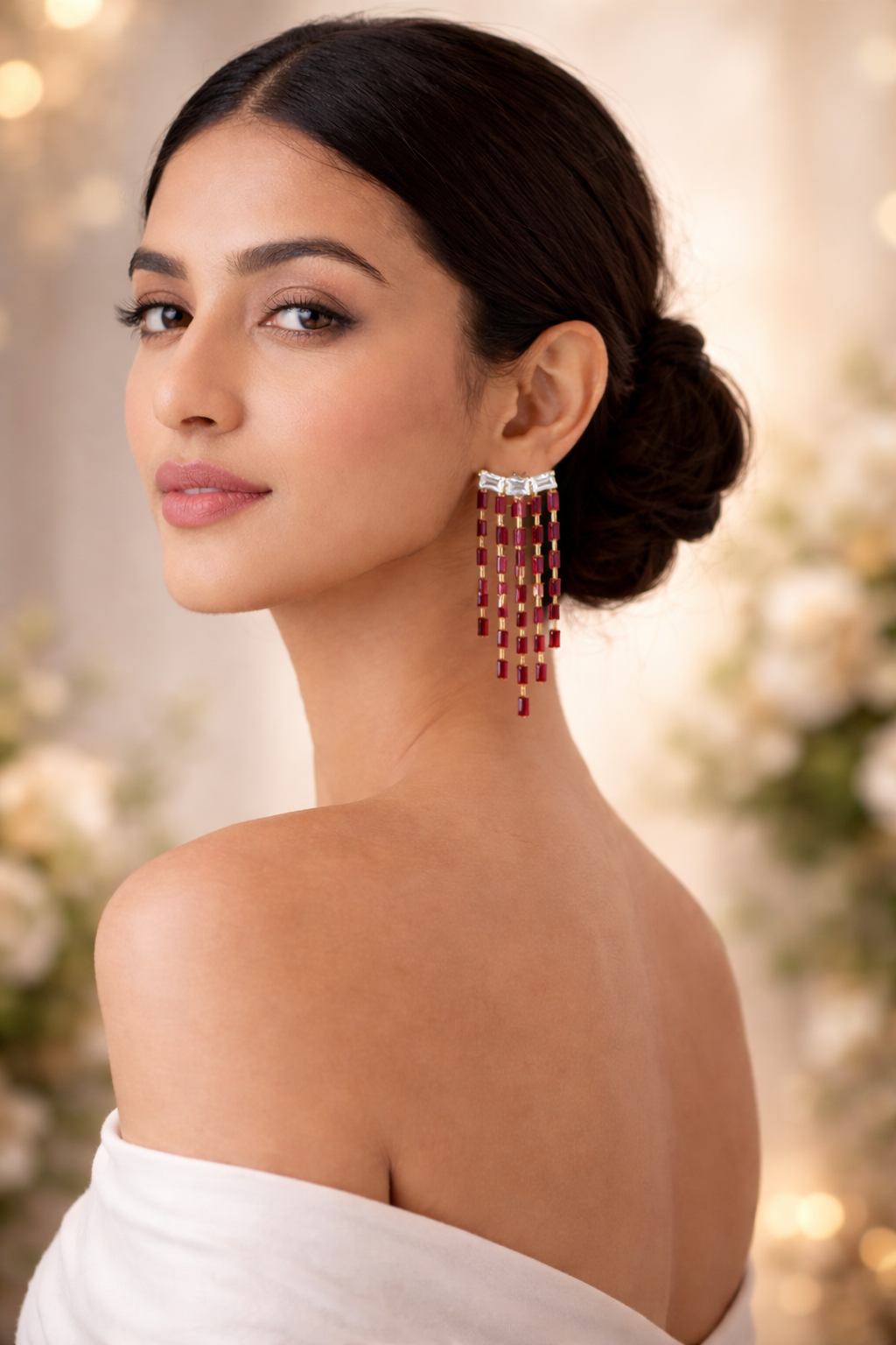 Woman wearing a pair of red and gold earrings with a blurred background