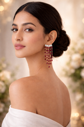 Woman wearing a pair of red and gold earrings with a blurred background