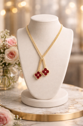 Gold necklace with red flower pendants on a white mannequin bust with a blurred floral background