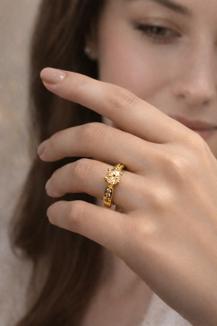 Close-up of a hand wearing a gold ring with a diamond on a neutral background
