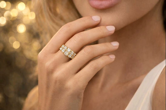 Close-up of a hand wearing a diamond ring with a blurred golden background