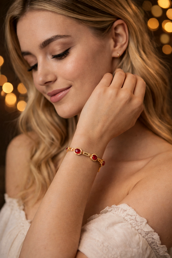 Woman wearing a gold bracelet with red stones against a warm, blurred background