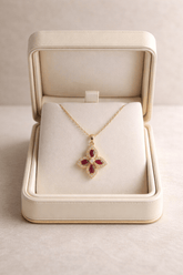 Gold necklace with a red pendant in an open jewelry box on a light gray background