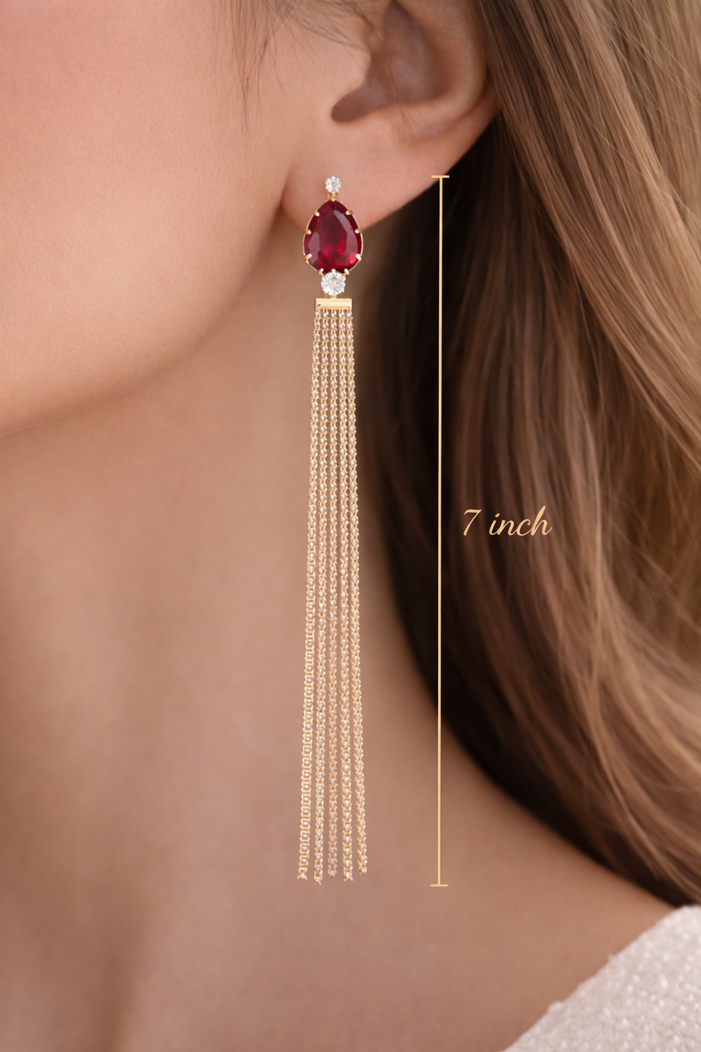 Earring with a red gemstone and gold tassels worn by a person, with &
