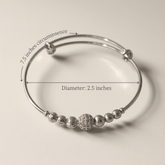 Silver beaded bracelet with measurements on a beige background