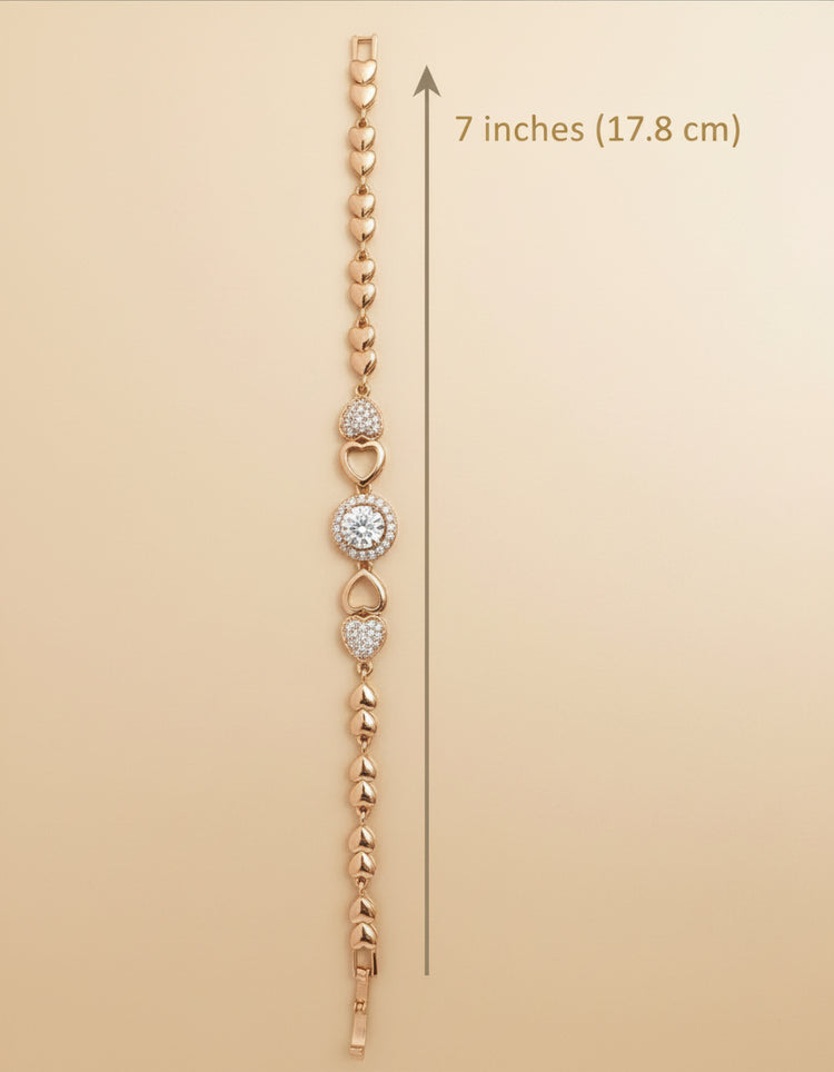 Rose gold bracelet with heart and round charm on a beige background, showing measurement of 7 inches.