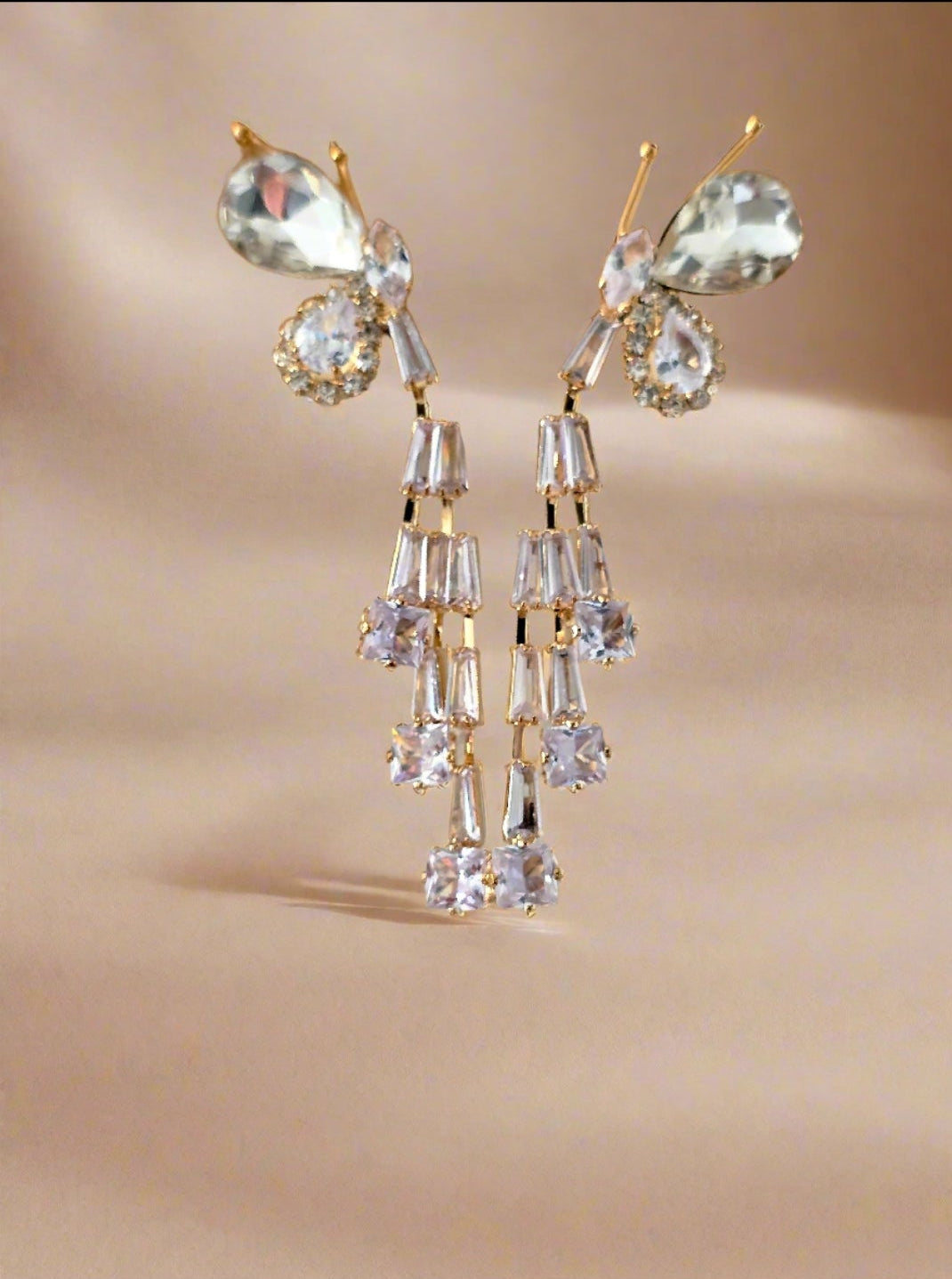 Gold and crystal earrings on a beige background