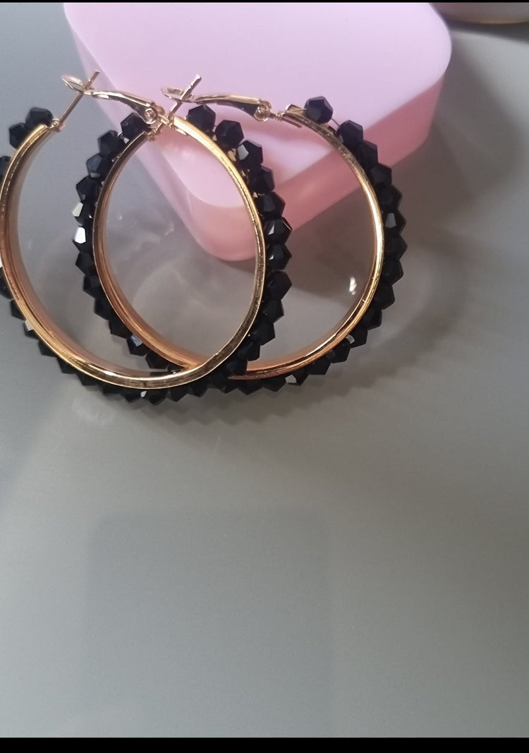 Gold hoop earrings with black beads on a white surface