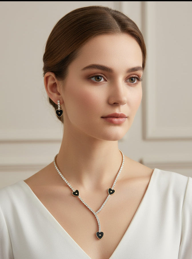 Woman wearing a necklace with black heart pendants against a neutral background