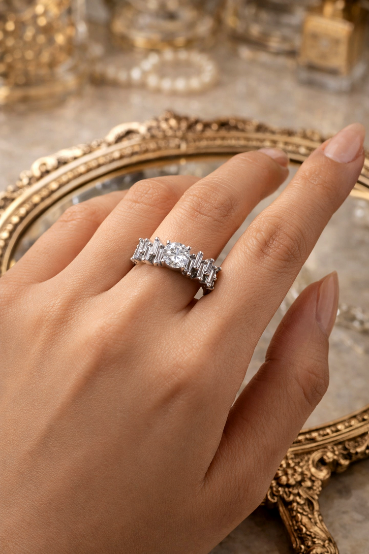 Hand wearing a diamond ring with a decorative mirror in the background