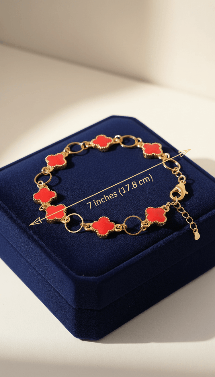 Gold bracelet with red clover-shaped charms on a blue jewelry box.