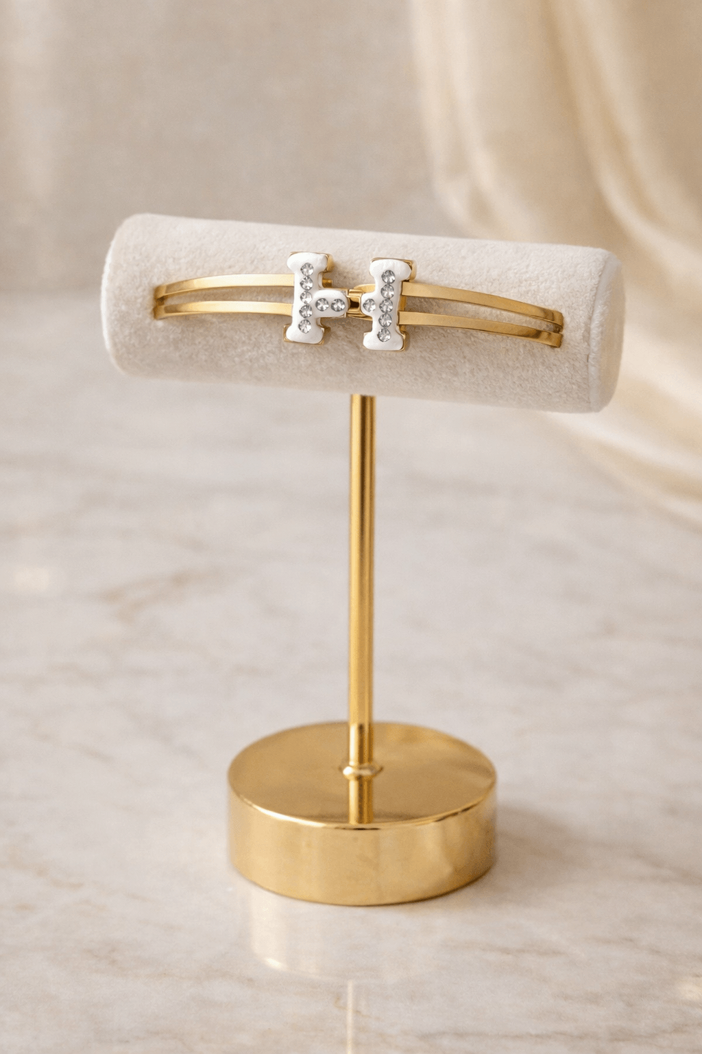 Gold bracelet on a stand with a beige background