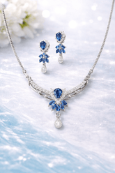 Jewelry set with necklace and earrings featuring blue gemstones on a light background