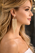 Close-up of a woman wearing gold tassel earrings with a blurred background