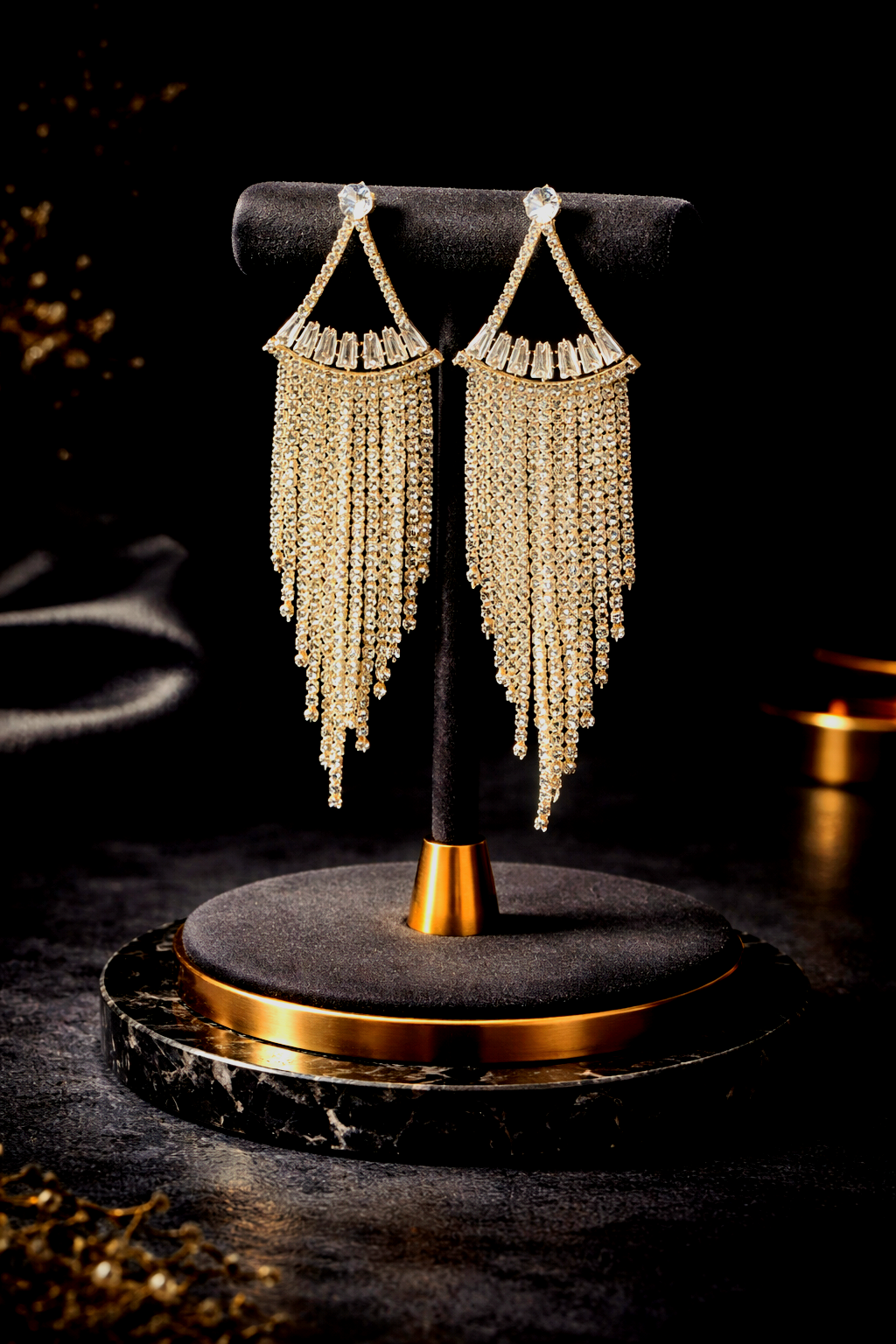 Pair of gold-framed beaded earrings on a black stand with a dark background