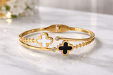 Gold bracelet with clover designs on a marble surface