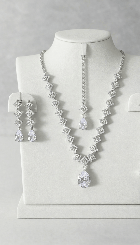 Silver necklace and earrings set on a mannequin bust against a gray background