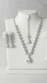 Silver necklace and earrings set on a mannequin bust against a gray background