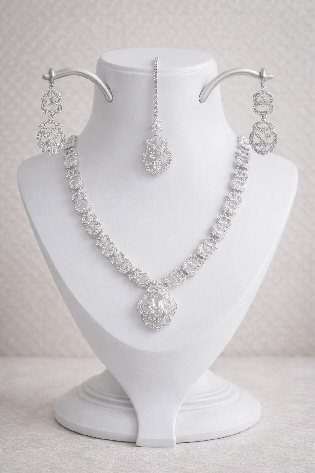 Silver necklace and earrings set on a white mannequin bust against a light background