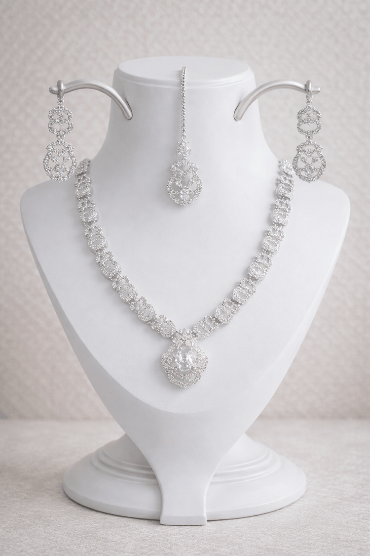 Silver necklace and earrings set on a white mannequin bust against a light background