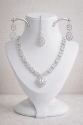 Silver necklace and earrings set on a white mannequin bust against a light background