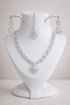 Silver necklace and earrings set on a white mannequin bust against a light background