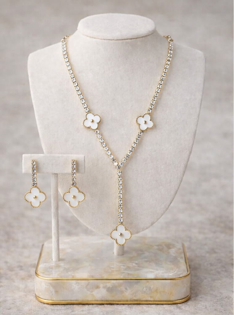 Necklace and earrings with floral designs on a white stand against a gray background