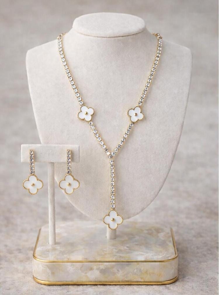 Necklace and earrings with floral designs on a white stand against a gray background