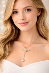 Woman wearing a gold necklace with a heart pendant against a neutral background