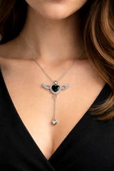 Necklace with a heart-shaped pendant worn by a person against a black background
