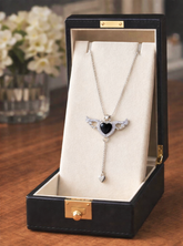 Jewelry box with a necklace featuring a heart pendant on a wooden surface.