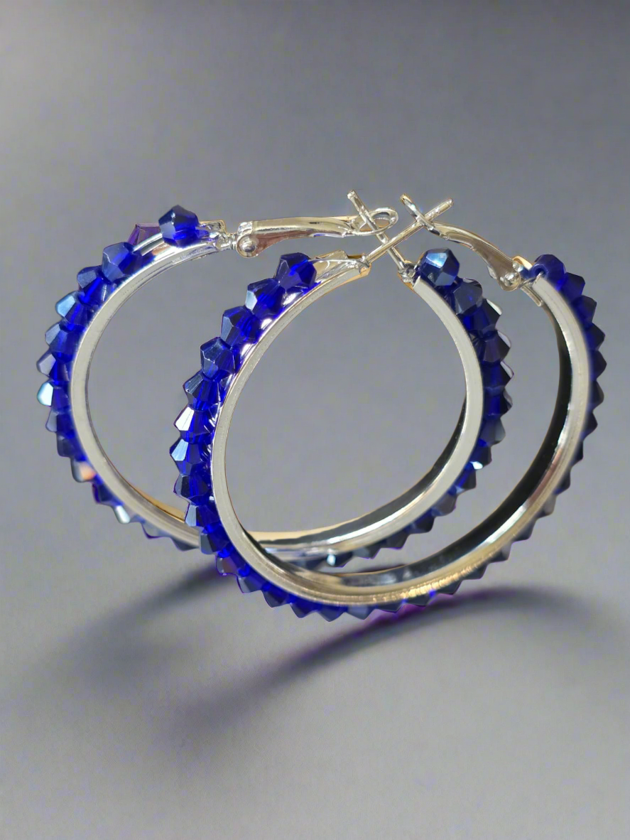 Hoop earrings with blue gemstones on a gray background