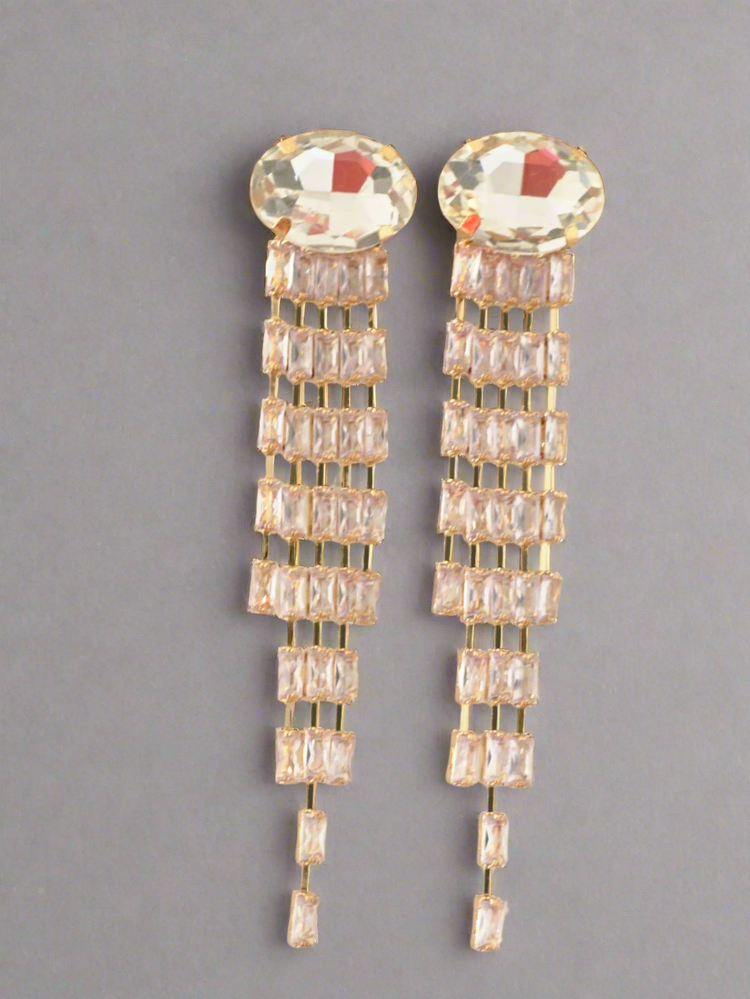 Pair of gold earrings with clear gemstones on a gray background