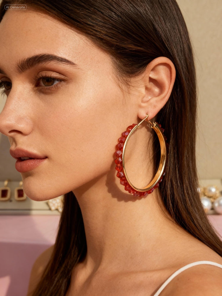 Close-up of a woman wearing gold hoop earrings with red beads.