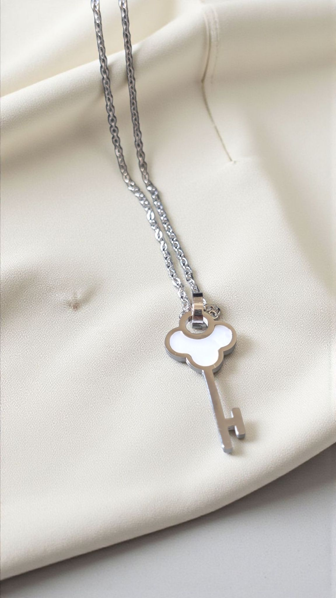 Silver key-shaped pendant necklace on a white background