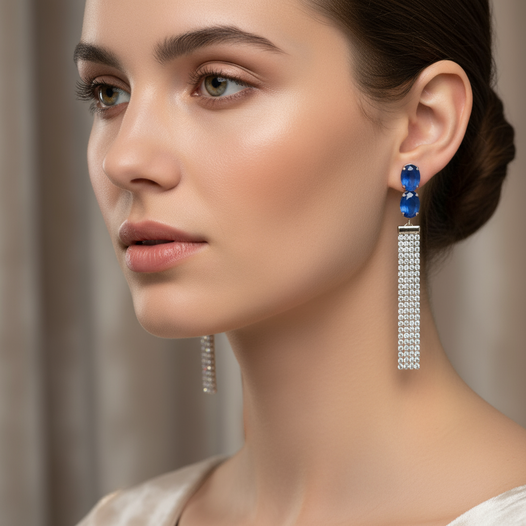 Close-up of a woman wearing blue gemstone earrings with a neutral background