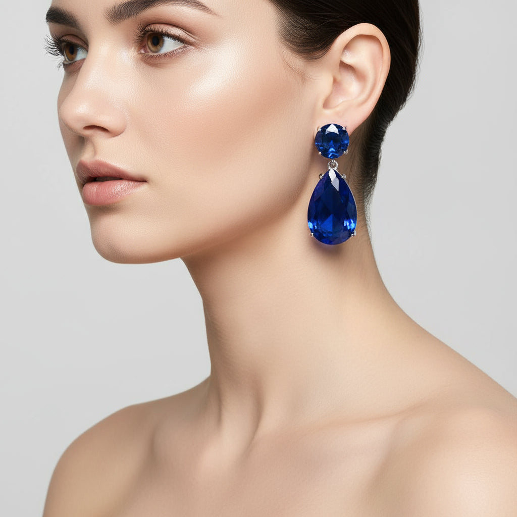 Woman wearing a pair of blue teardrop earrings against a neutral background