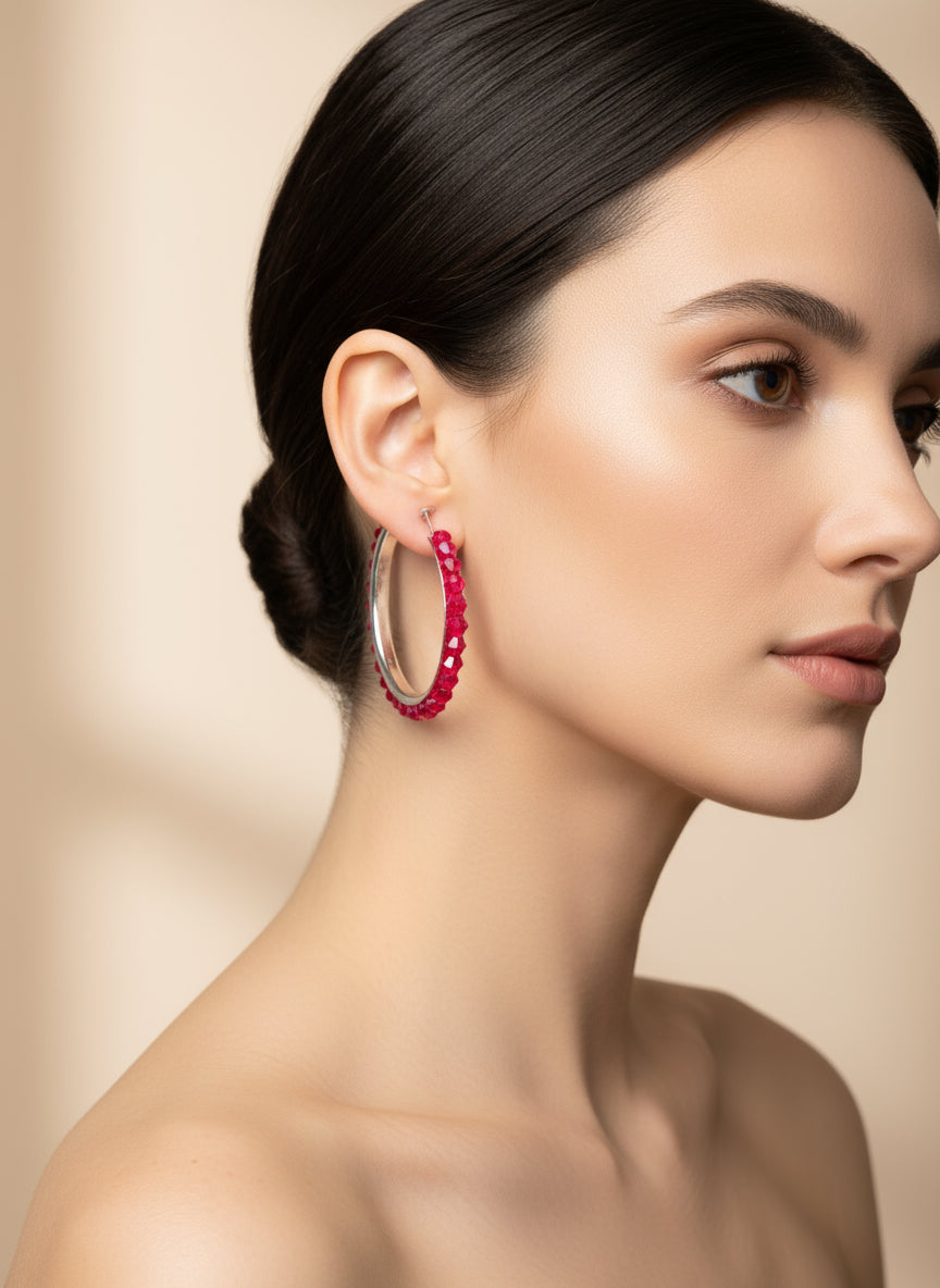 Woman wearing red hoop earrings against a beige background