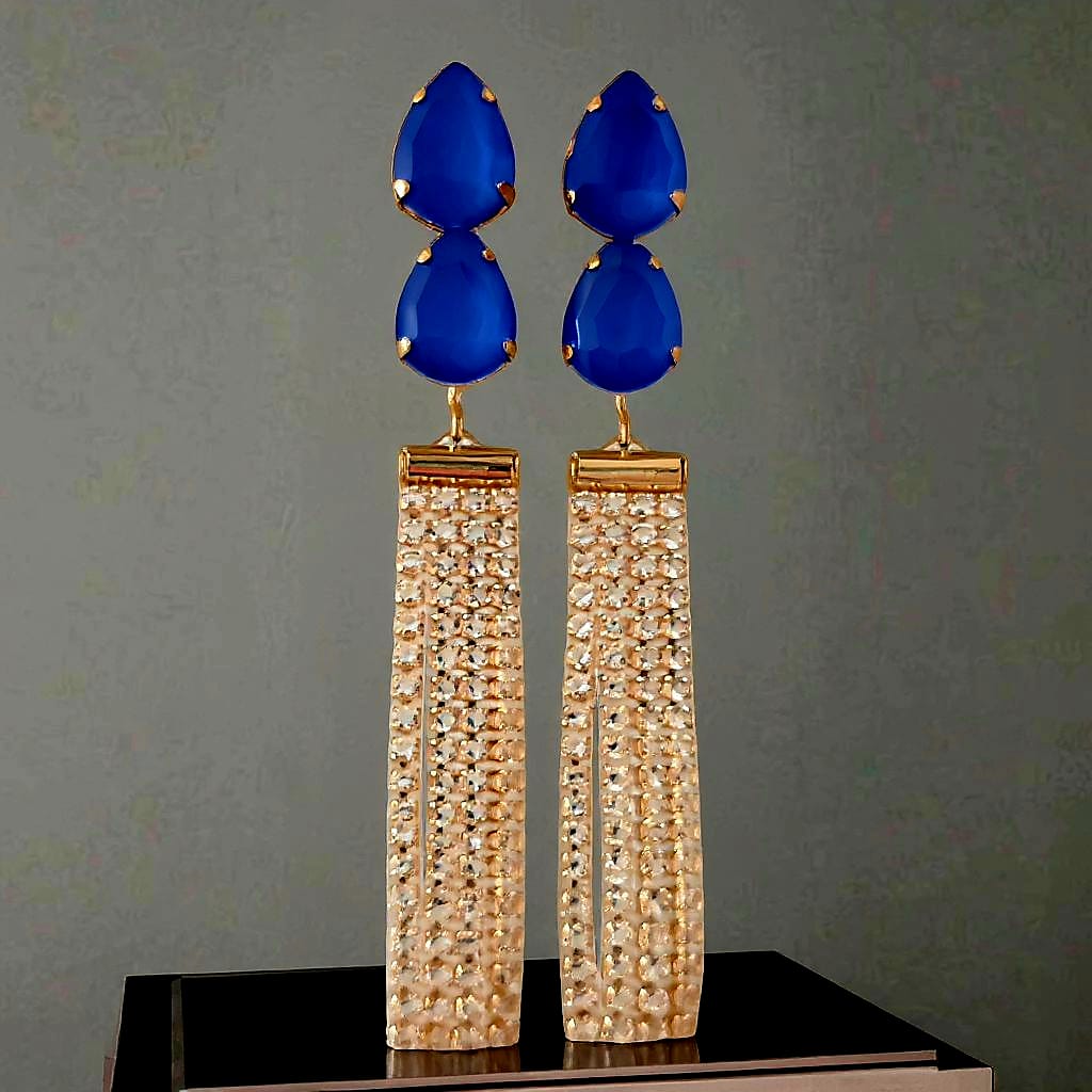 Pair of blue teardrop earrings with gold accents on a gray background