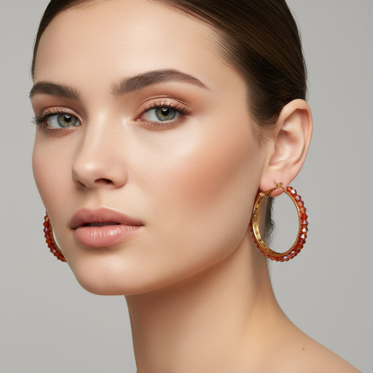 Gold hoop earrings with red beads on a silver background