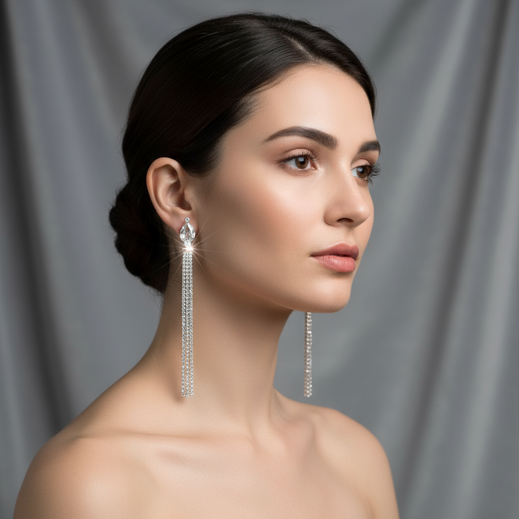 Woman wearing long, dangling earrings against a gray background