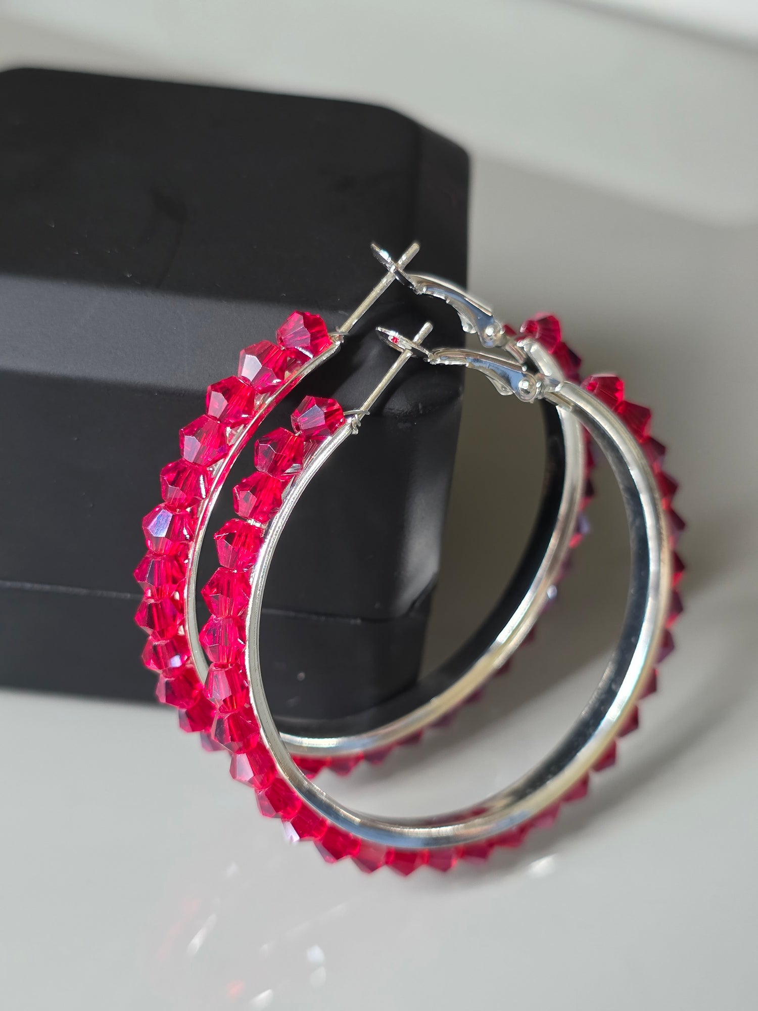 Silver hoop earrings with red gemstones on a white surface