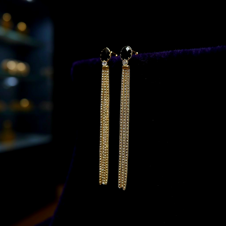 Gold earrings with black stones on a dark background